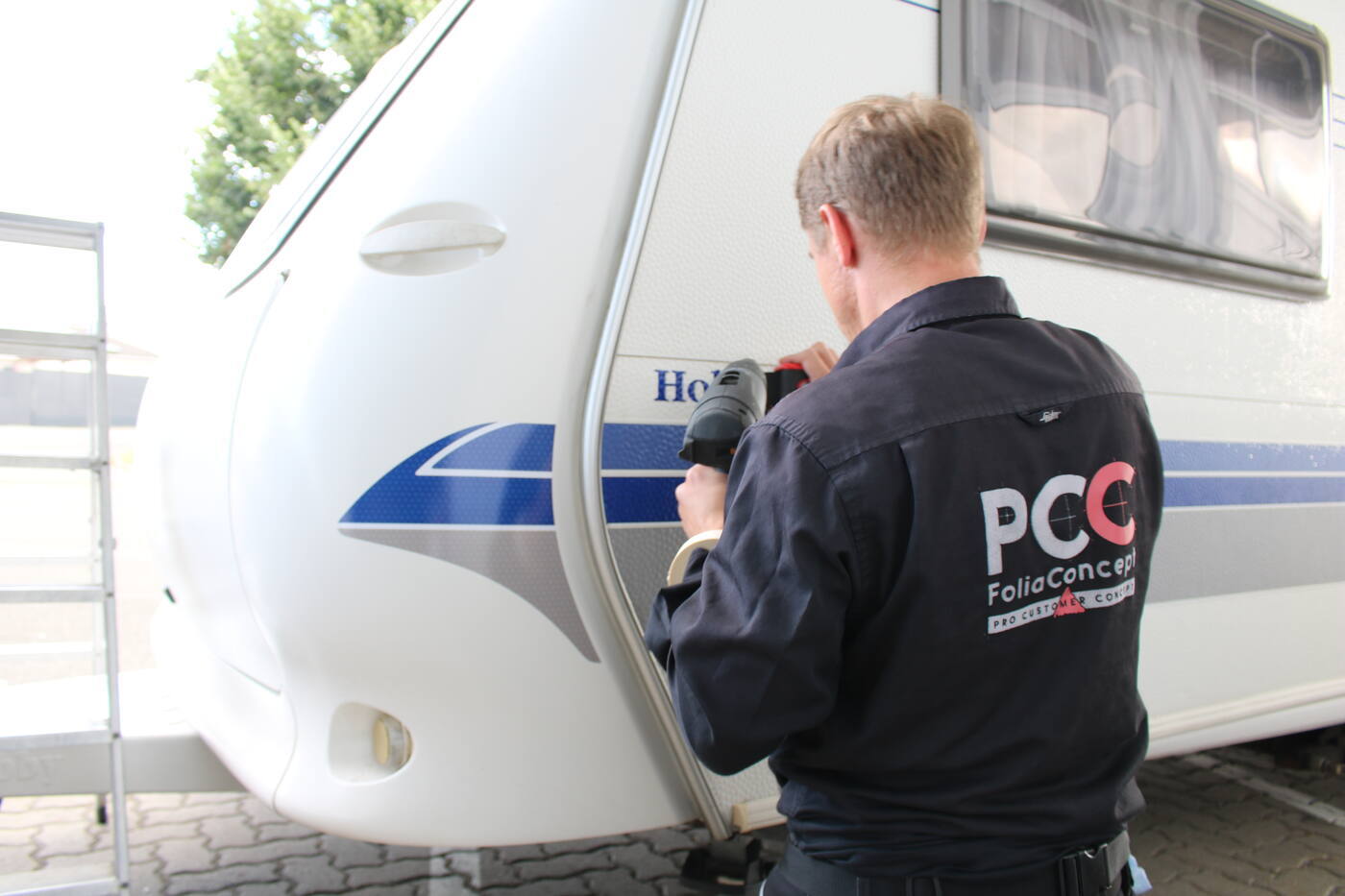 PCC-Mitarbeiter bringt ein Dekor an der Front eines Hobby-Wohnwagens an